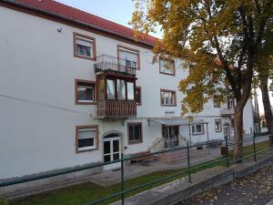 a white building with a balcony on the side of it at Kuckó Apartman Berente in Berente