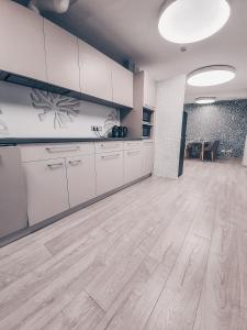 an empty kitchen with white cabinets and a wooden floor at Pervaža in Panevėžys