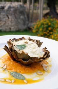 a piece of artichoke on a white plate with sauce at Masseria Borgo Santuri in Ostuni