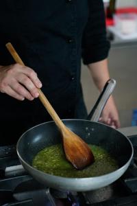 a person stirring a pan with a wooden spoon at Masseria Borgo Santuri in Ostuni