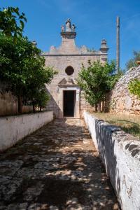 an old stone building with a gate and trees at Masseria Borgo Santuri in Ostuni