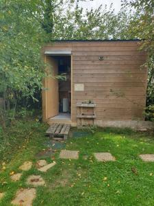 een houten schuur met een deur en een bank in een tuin bij Yourtes 6 personnes proche provins et disney in Bannost
