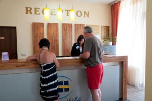 a man and a woman standing at a reception counter at Apart Hotel Harmony Hills Residence in Rogachevo