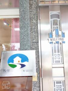 un panneau de bienvenue sur la porte d'un bâtiment dans l'établissement 一見鐘情獨棟包棟民宿, à Wei-ch'ien