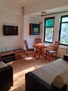 sala de estar con mesa, sillas y TV en Lester Apartments, en Skopje