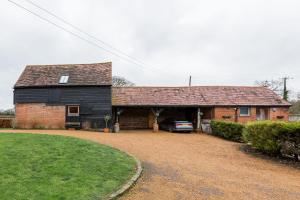 a black barn with a car parked in a driveway at Old Barn Cottage in Horley