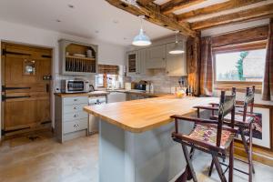 a kitchen with a wooden counter top and chairs at Old Barn Cottage in Horley