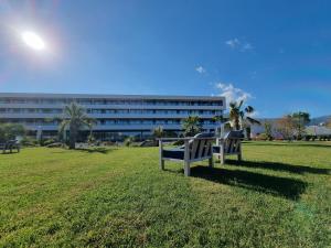 two benches sitting in a field in front of a building at Golden Tulip Porto-Vecchio in Porto-Vecchio