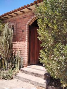 un bâtiment en briques avec une porte en bois et un cactus dans l'établissement Chalé Rústico, à Palmeiras