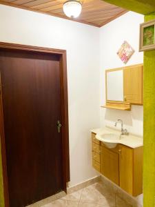 uma casa de banho com um lavatório e uma porta castanha em Chácara - PÉ NA REPRESA A 1H30 DE SP em Joanópolis