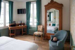a bedroom with a bed and a mirror and a chair at Hotel de Charme La Bonne Adresse - Logis hotels in Le Havre
