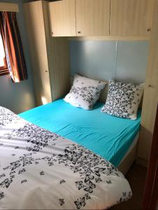 sypialnia z łóżkiem z niebieskim kocem i poduszkami w obiekcie Le chalet de Baptiste w mieście Saint-Michel