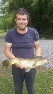 un homme tenant un poisson entre ses mains dans l'établissement Le chalet de Baptiste, à Saint-Michel