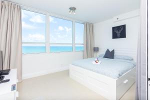 a white bedroom with a bed and a large window at Girasole Rentals in Miami Beach