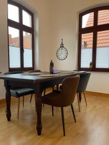 a dining room table with chairs and a clock on the wall at Charmante Ferienwohnung mit Terrasse im Herzen von Norden in Norden