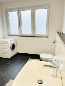 uma casa de banho com um lavatório e uma máquina de lavar roupa em Charmante Ferienwohnung Greta em Norden