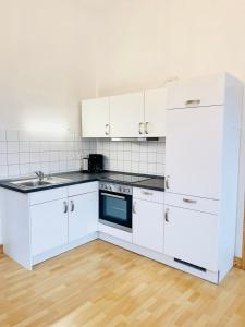 a kitchen with white cabinets and a stove top oven at Charmante Ferienwohnung Greta in Norden