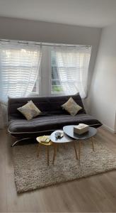 sala de estar con sofá negro y mesa en Petit cocon proche gare et commerces, en Chantilly