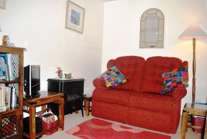 ein Wohnzimmer mit einem roten Stuhl und einem TV in der Unterkunft Crepigill Cottage in Portree