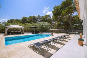einen Pool mit Stühlen und einem Pavillon in der Unterkunft Menorca Villa Marbella in Son Parc