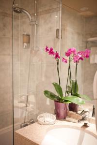 um vaso de flores cor-de-rosa sentado num lavatório na casa de banho em Hotel Louvre Sainte Anne em Paris
