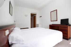 a white bedroom with a bed and a television at Villa Miel in Cala Millor