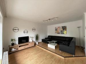 a living room with a black couch and a flat screen tv at Moderne, helle Wohnung mit Terasse 15min bis OB Centro in Dinslaken
