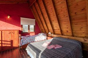 une chambre avec deux lits dans une cabane en rondins dans l'établissement Patagonia Cabañas, à Las Gaviotas