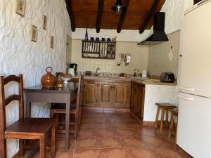 uma cozinha com armários de madeira, uma mesa e um frigorífico em Casa rural las perez em Granadilla de Abona