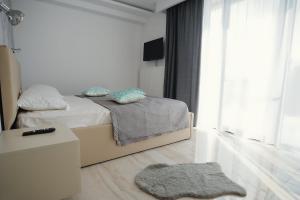a white bedroom with a bed and a rug at Casa IANIS Turda in Turda