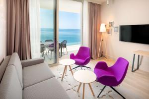 a living room with purple chairs and a large window at Radisson Blu Resort & Spa in Split