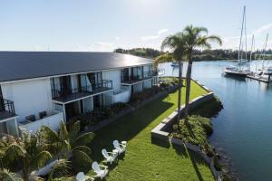 a house next to a river with chairs and a boat at Sails Port Macquarie by Rydges in Port Macquarie