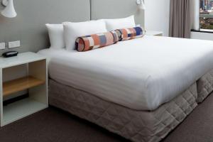a bedroom with a large white bed with a night stand at Rydges Parramatta in Sydney