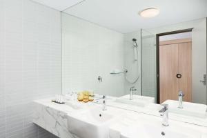 a bathroom with two sinks and a large mirror at Rydges Parramatta in Sydney