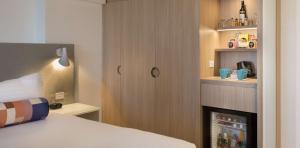 a bedroom with a bed and a cupboard with a refrigerator at Rydges Parramatta in Sydney