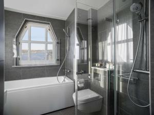 a bathroom with a tub and a toilet and a shower at Radisson Collection, Strand Hotel, Stockholm in Stockholm +37 photos