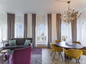 a living room with a couch and a table and chairs at Radisson Collection, Strand Hotel, Stockholm in Stockholm