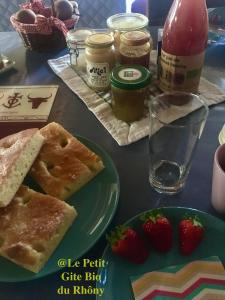 una mesa con un plato de comida y fresas. en Le petit gite Bio du Rhôny, en Le Cailar