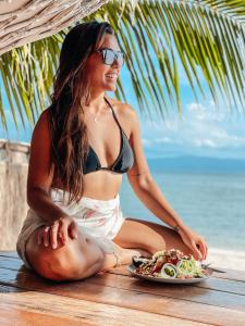 a woman sitting on a table with a plate of food at Sea Love Beach Bar & Bungalows in Ban Tai