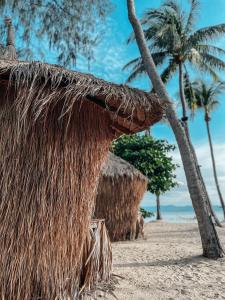 a straw hut on the beach with a palm tree at Sea Love Beach Bar & Bungalows in Ban Tai