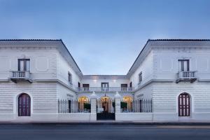 un grande edificio bianco con cancello di Hotel la Perla Leon a León