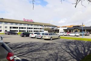 a parking lot with cars parked in front of a building at Scandic Helsingborg Nord in Helsingborg