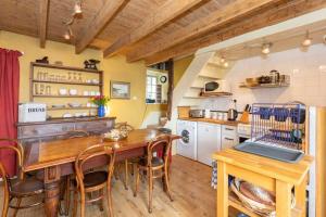 a kitchen with a wooden table and chairs and a kitchen with a stove at The Cottage By The Sea, Scotland in Burnmouth