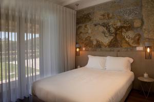 a bedroom with a white bed and a large window at Casa do Sobreiro in Celorico de Basto