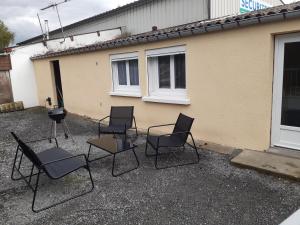 um grupo de cadeiras e uma grelha em frente a uma casa em Gîte la Parent'Aise em Fressenneville