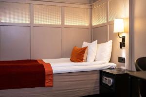 a hotel room with a bed with an orange pillow at Scandic Grand Central in Stockholm