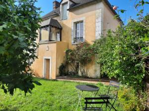 a table and chair in front of a house at Maison avec jardin dans petit bourg typiquement Percheron - Le Colombier in Boissy-Maugis