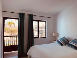 ein Schlafzimmer mit einem Bett und einem großen Fenster in der Unterkunft VIVIENDA ÚNICA EN PRIMERA LÍNEA DE PLAYA in San Bartolomé de Tirajana