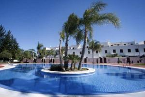 une grande piscine avec des palmiers en face d'un bâtiment dans l'établissement Apartment front Line La Cala Golf Resort, à La Cala de Mijas