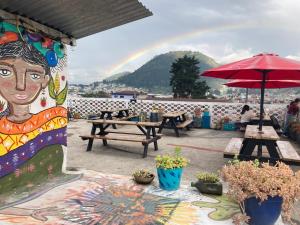 une peinture murale d'une femme avec un arc-en-ciel en arrière-plan dans l'établissement Kasa Kiwi Hostel & Travel Agency, à Quetzaltenango